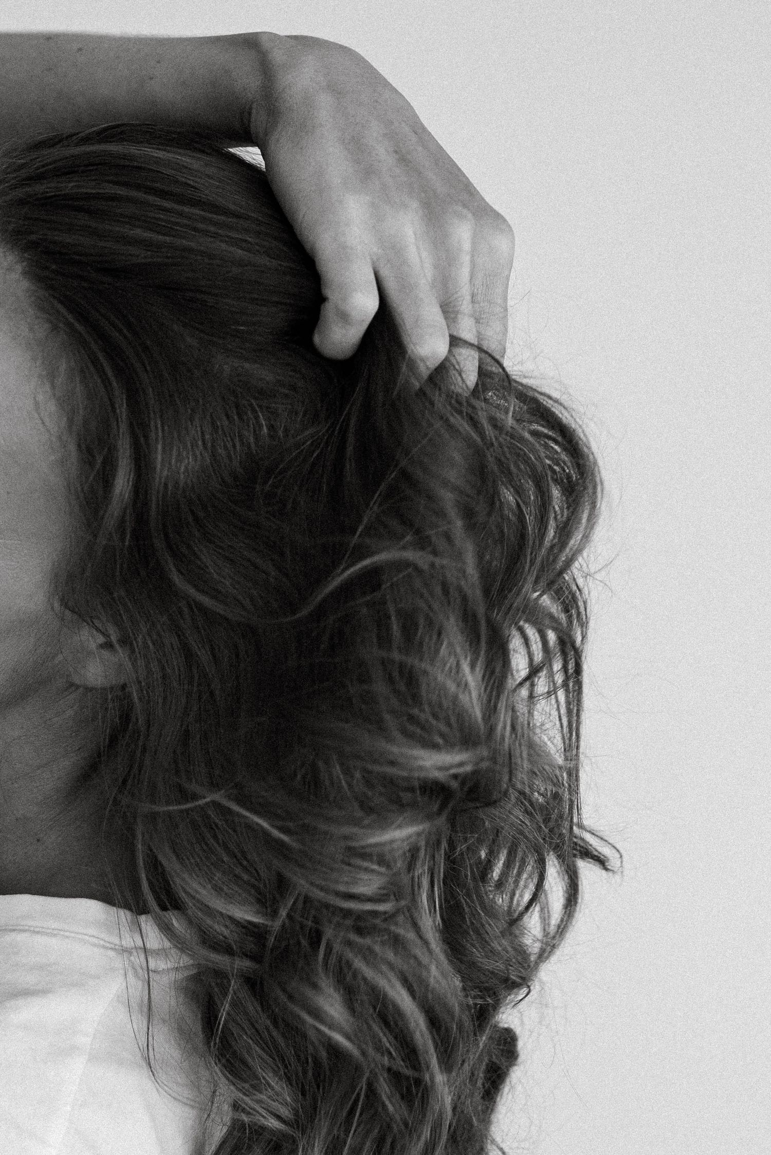 Close up of hand running through long wavy dark hair in black and white.