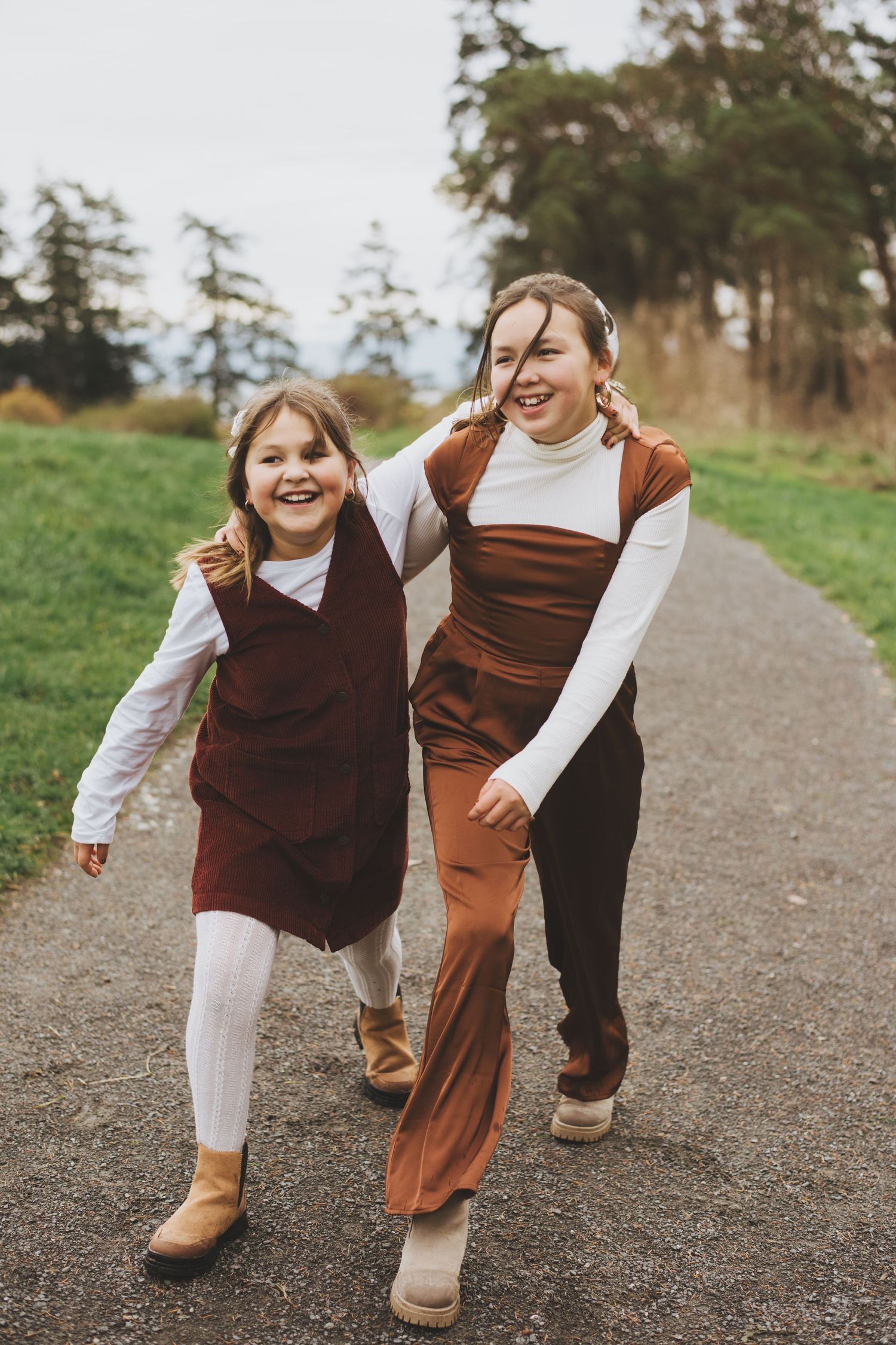 Sisters laughing and running hand in hand down a path.