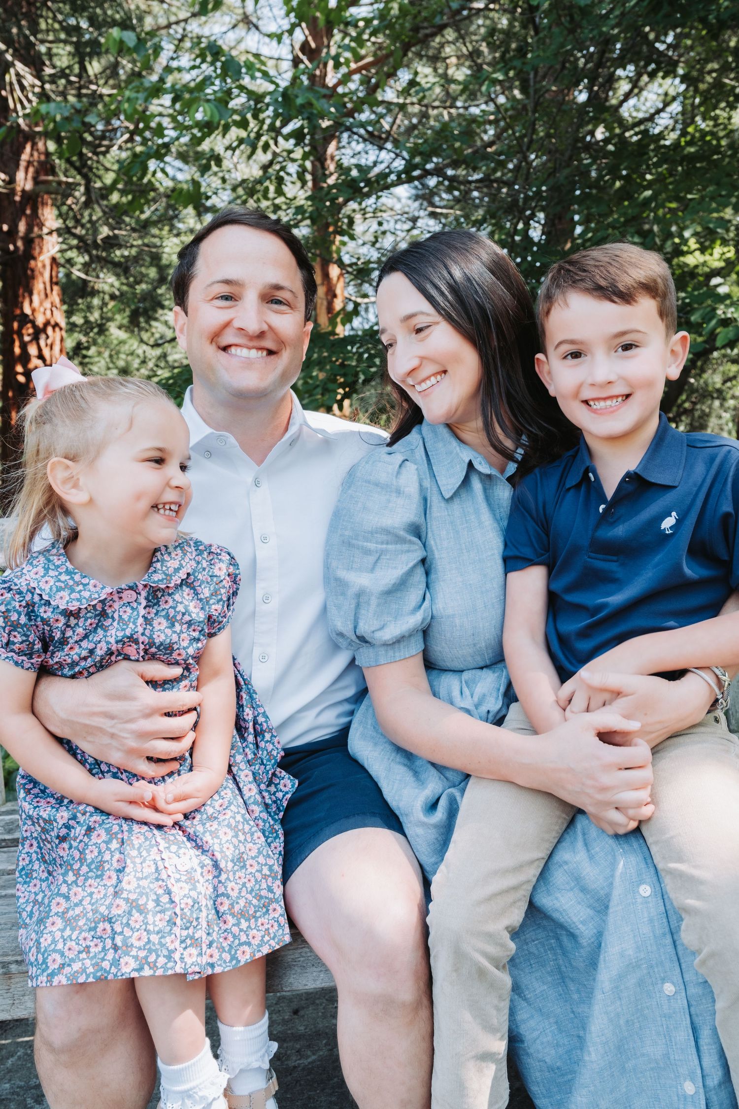 A seaside family portrait featuring casual summer attire and bright smiles.