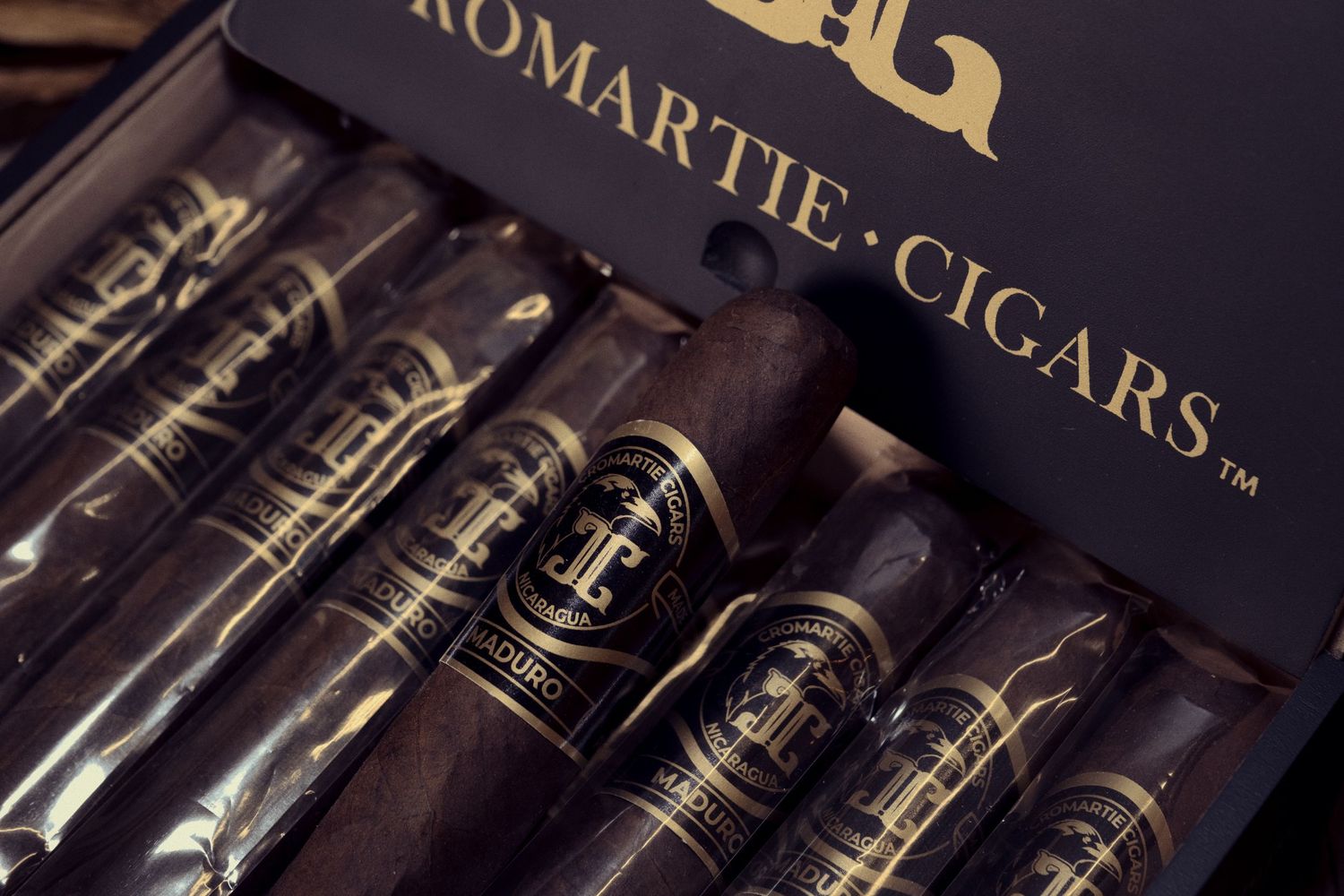 Premium dark cigars lined up in a luxurious Romartie Cigars branded display box.