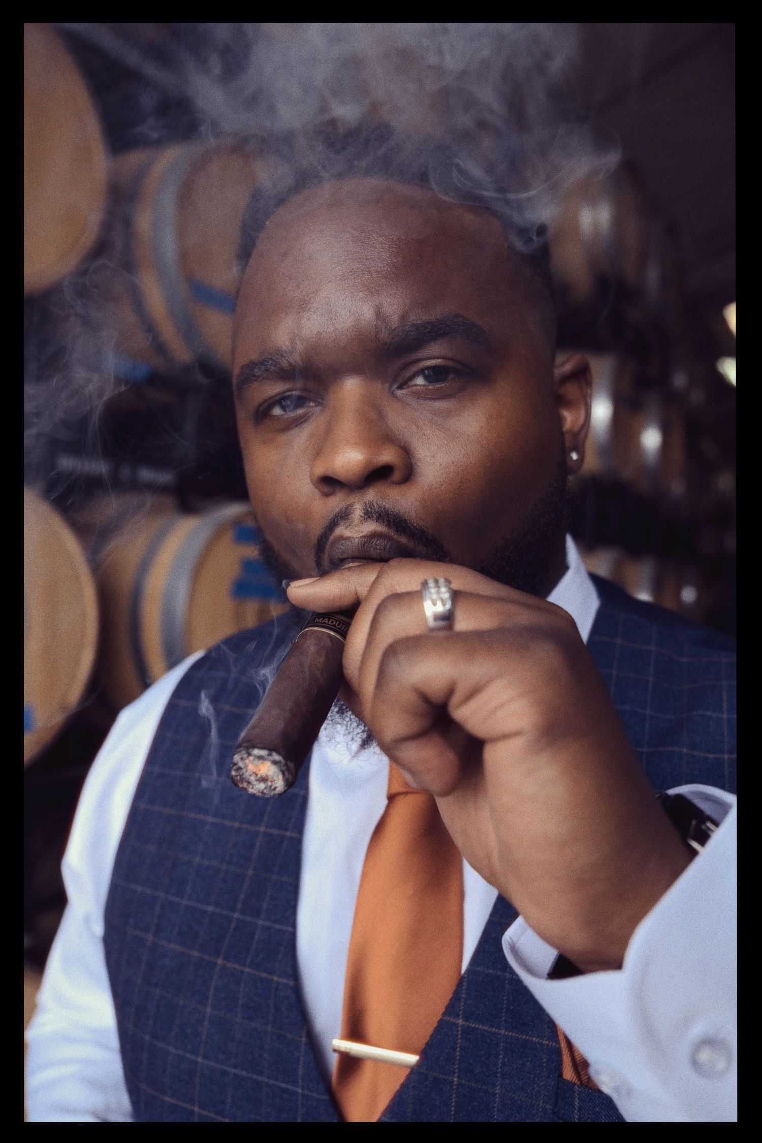 A person in a navy pinstripe suit jacket smoking a cigar follows several frames of their varied facial expressions.