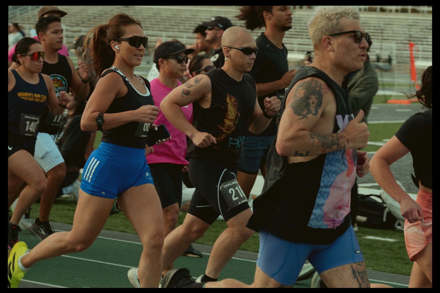 Group of runners competing in a track and field event wearing athletic gear and sunglasses.