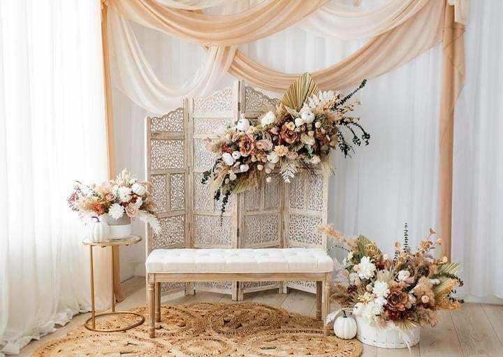 Elegant wedding seating area with white drapes, floral arrangements and a vintage screen backdrop.