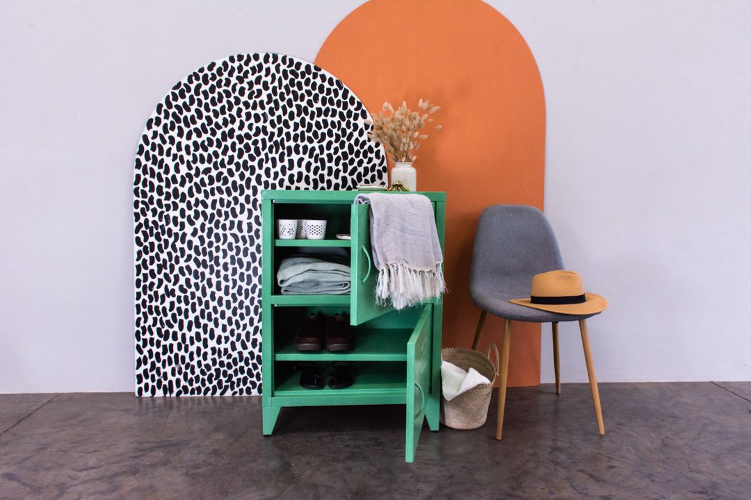 Contemporary room decor featuring a green ladder shelf against a color-blocked wall with orange and black pattern details.