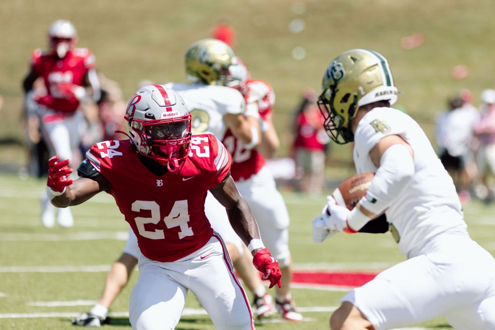 Football players in red and white uniforms competing during a sunny day game.