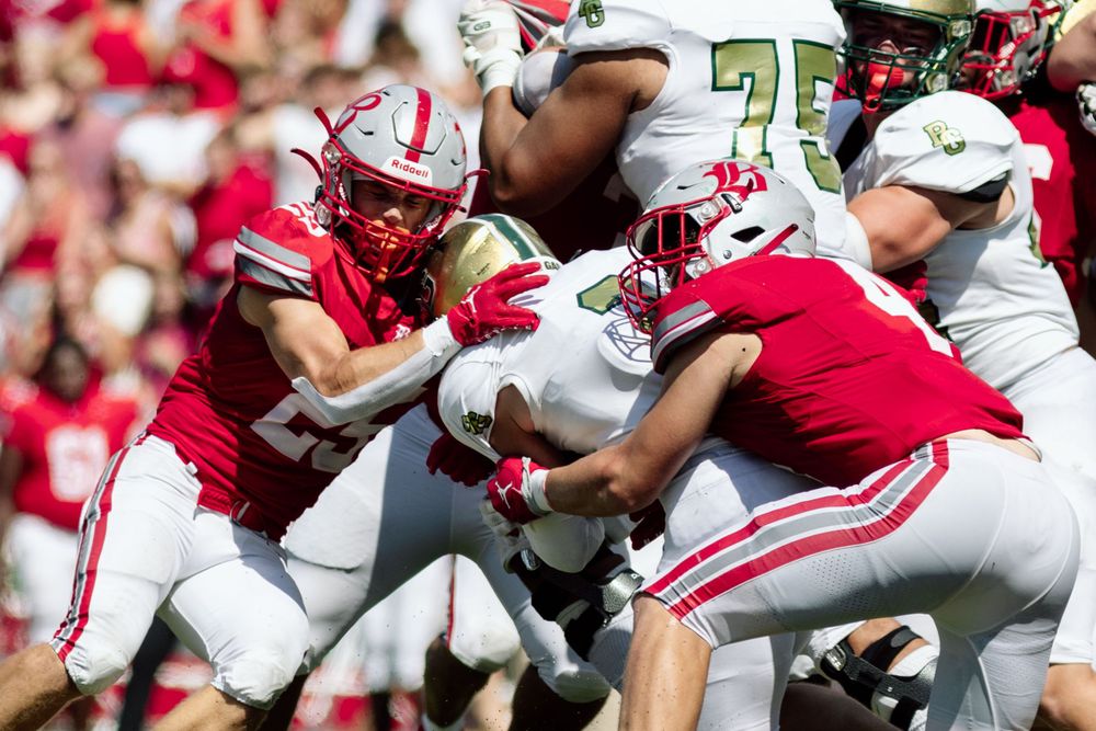 Football players colliding during an intense tackle on the field.