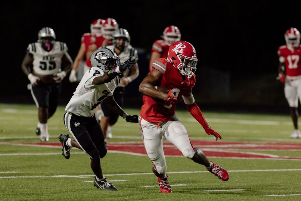 Football players in red and white uniforms competing during a nighttime game.