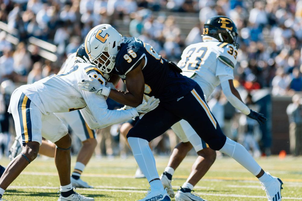 Two football players engage in intense physical contact during a collegiate match.