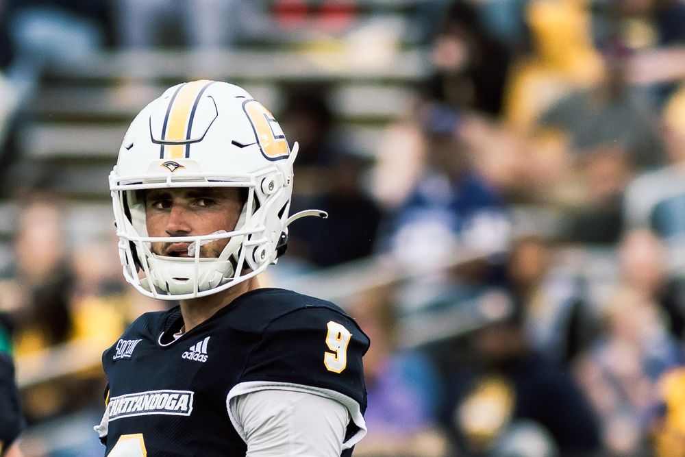 Football player in white uniform and helmet on field during game.