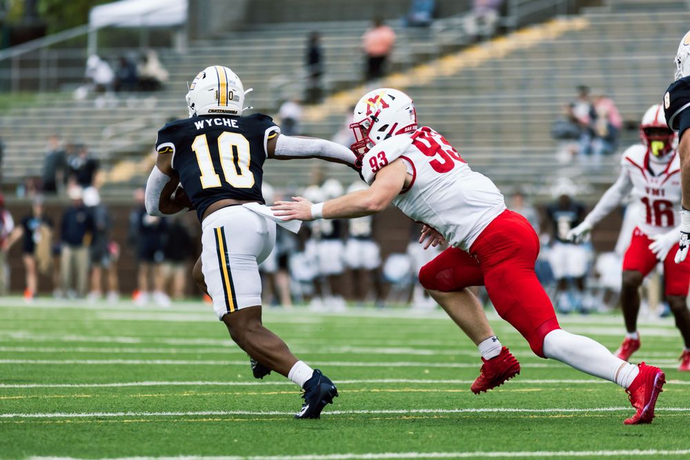 Two football players in action during tackle attempt on field.