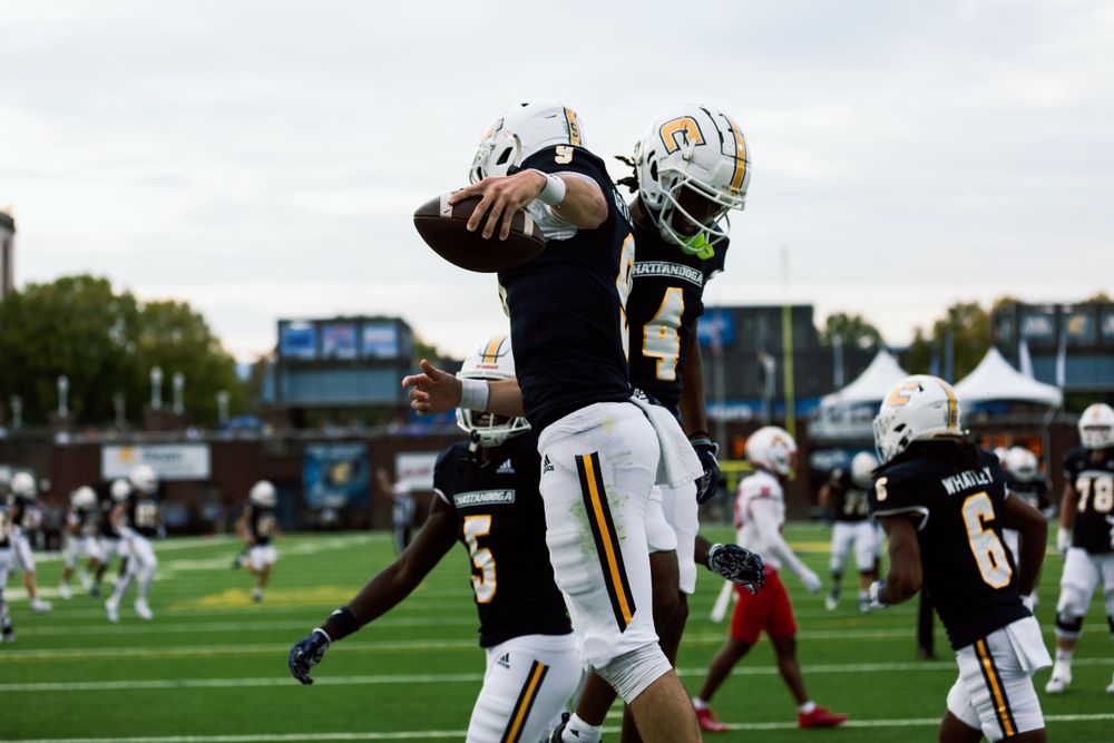 Football players jumping to catch ball during competitive game.