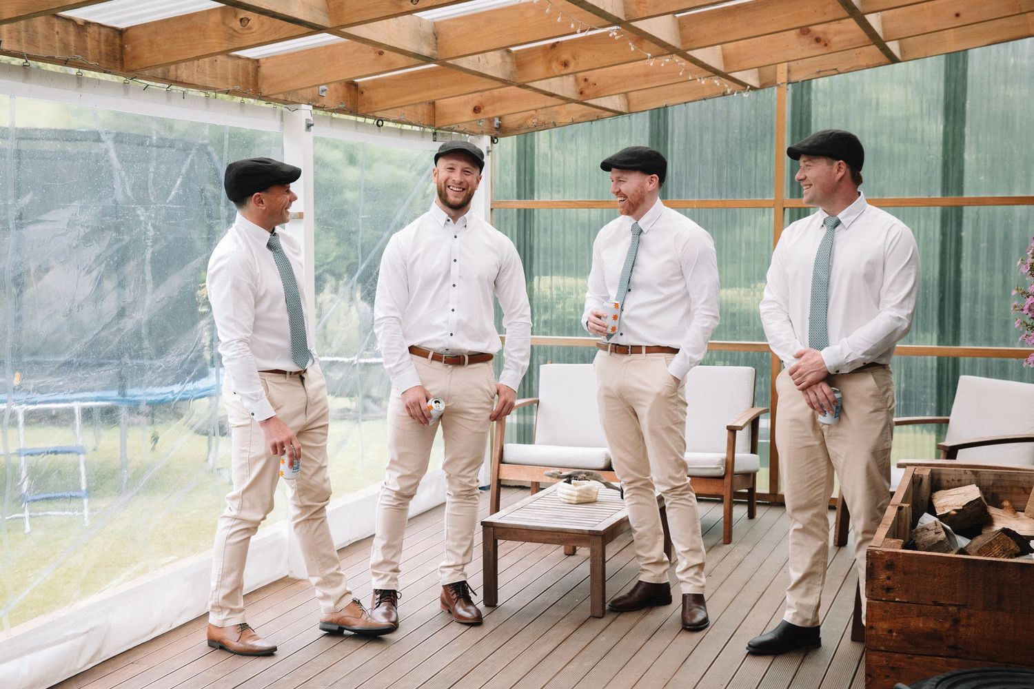Groomsmen in matching light colored suits having a conversation on outdoor deck.