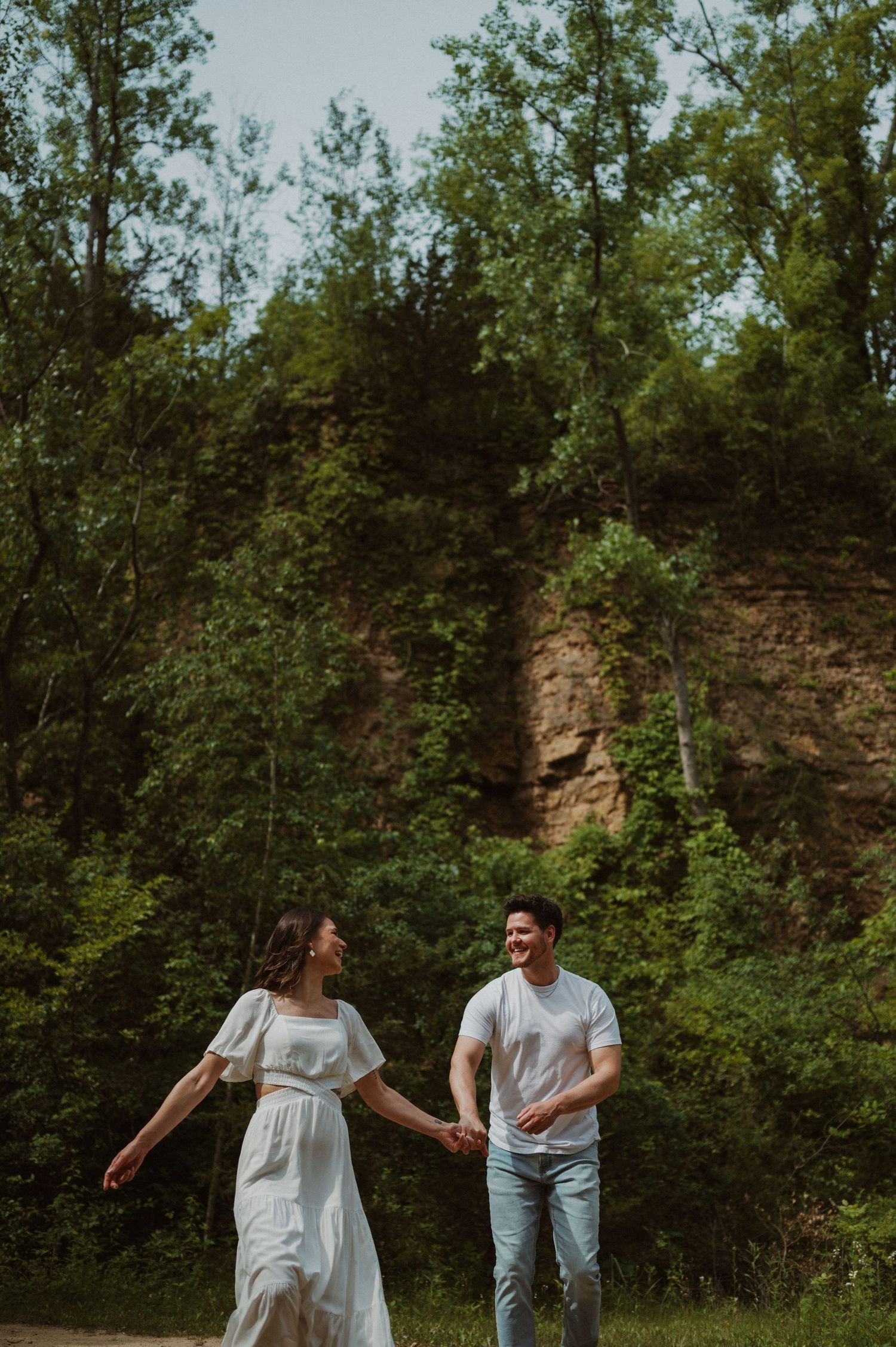 Two people share a joyful interaction while standing on a trail surrounded by greenery.