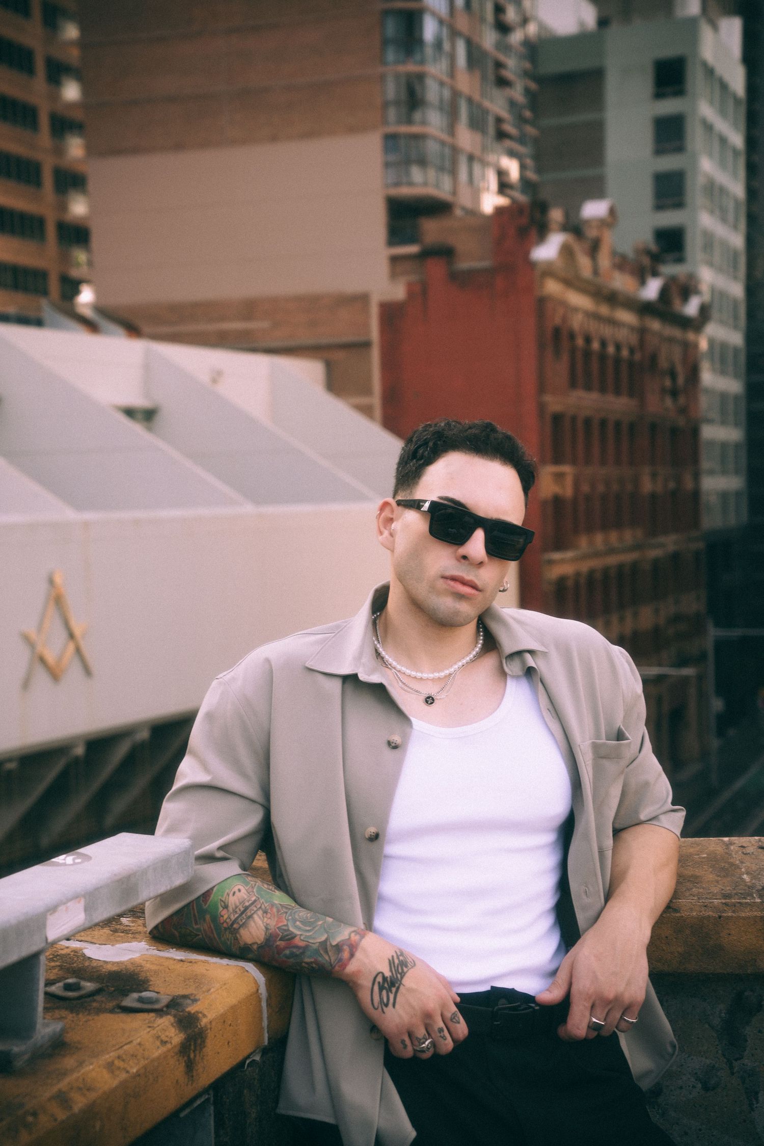 Urban rooftop portrait with person in beige jacket and white tank top.