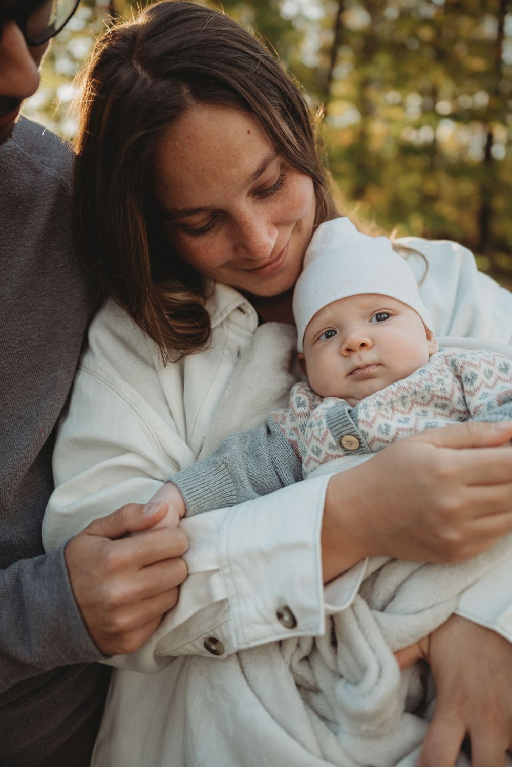 A tender family moment captured as parents cuddle their infant in warm autumn light.