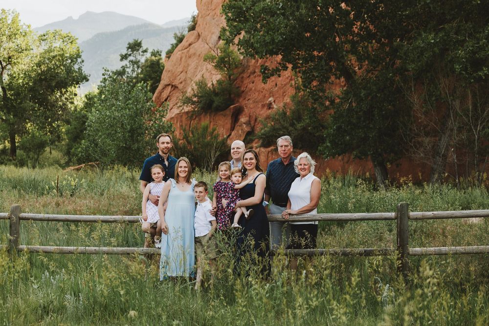 A series of outdoor family portraits taken against red rock formations and grassy fields at sunset.
