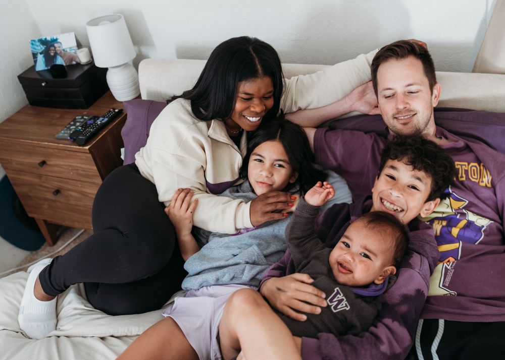 Happy family cuddling and laughing together on bed.