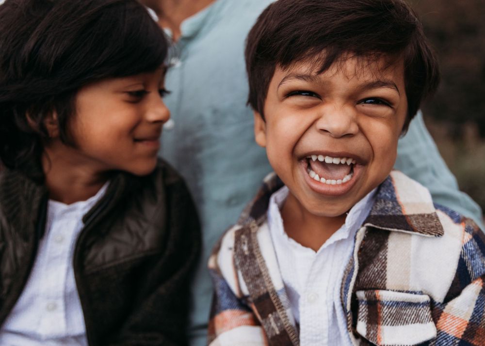 Two children share a candid laughing moment together outdoors.