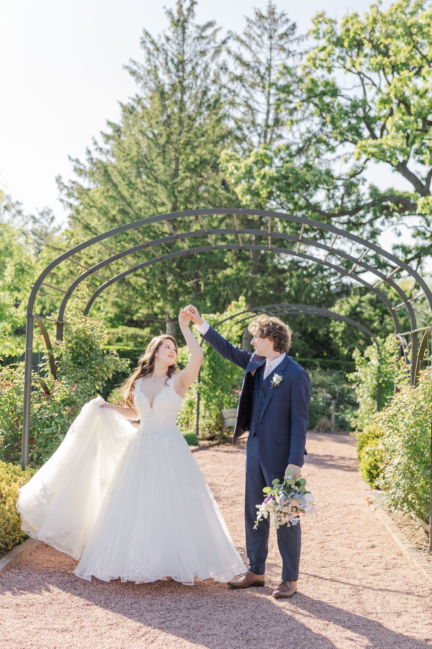 Wedding party walking in a lovely garden archway during golden hour photography session at a scenic outdoor venue.