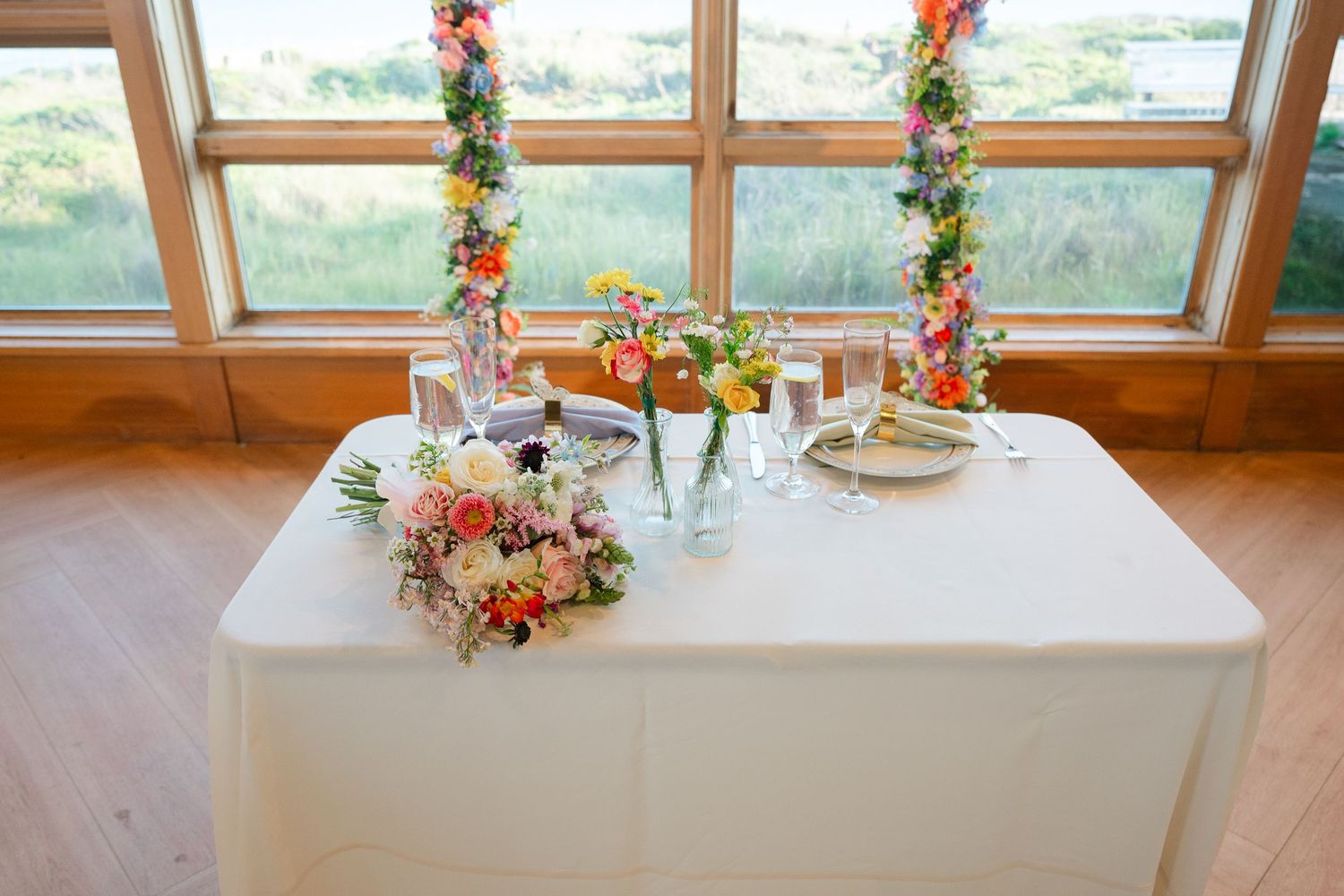 A elegant banquet table adorned with floral centerpieces and place settings next to large windows with natural light.