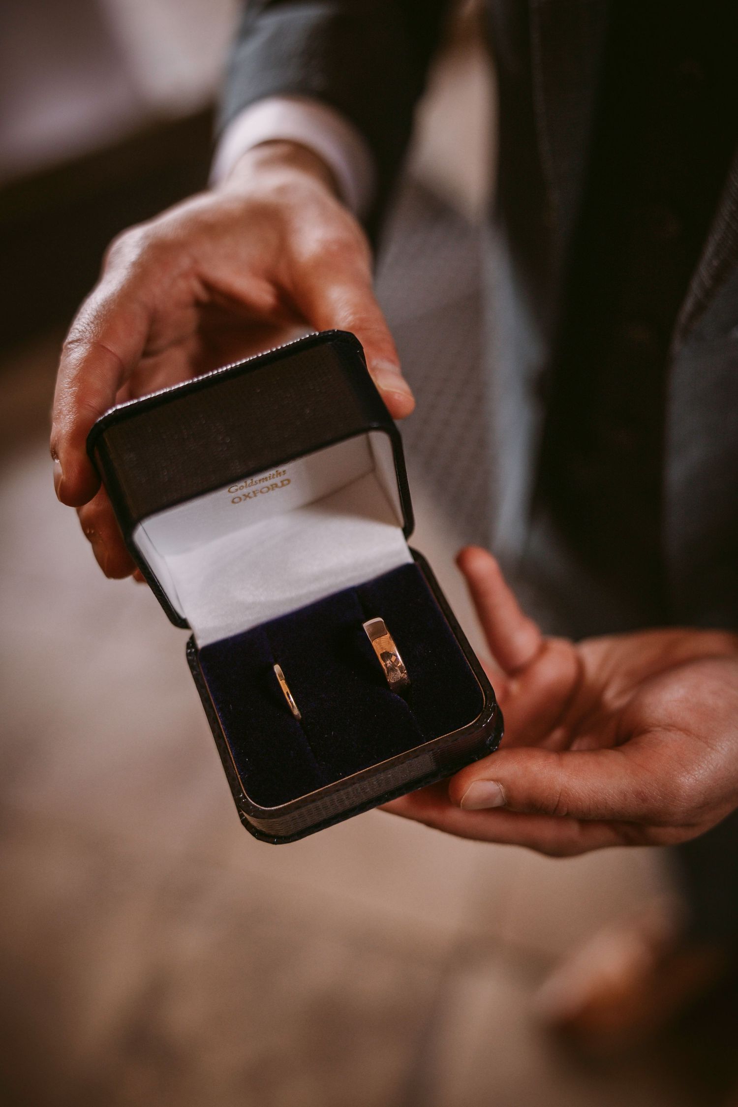 Hands showing different angles of a small black leather wallet or cardholder with gold accents.