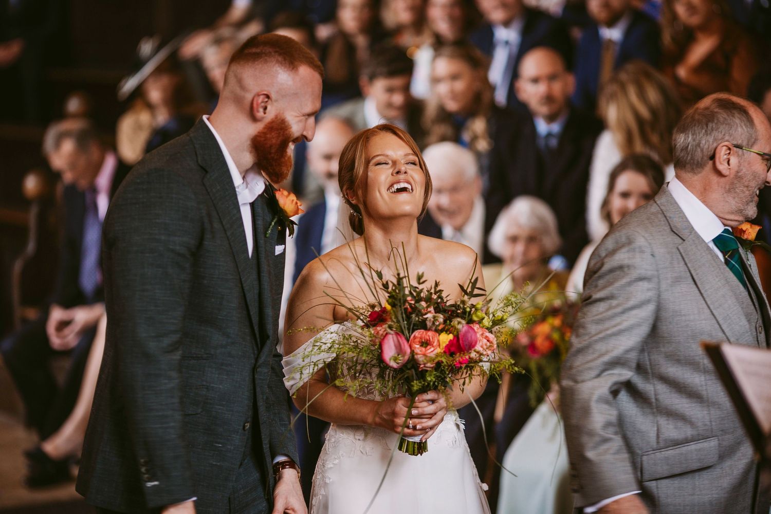 A joyous candid moment between newlyweds sharing laughter during their wedding ceremony.
