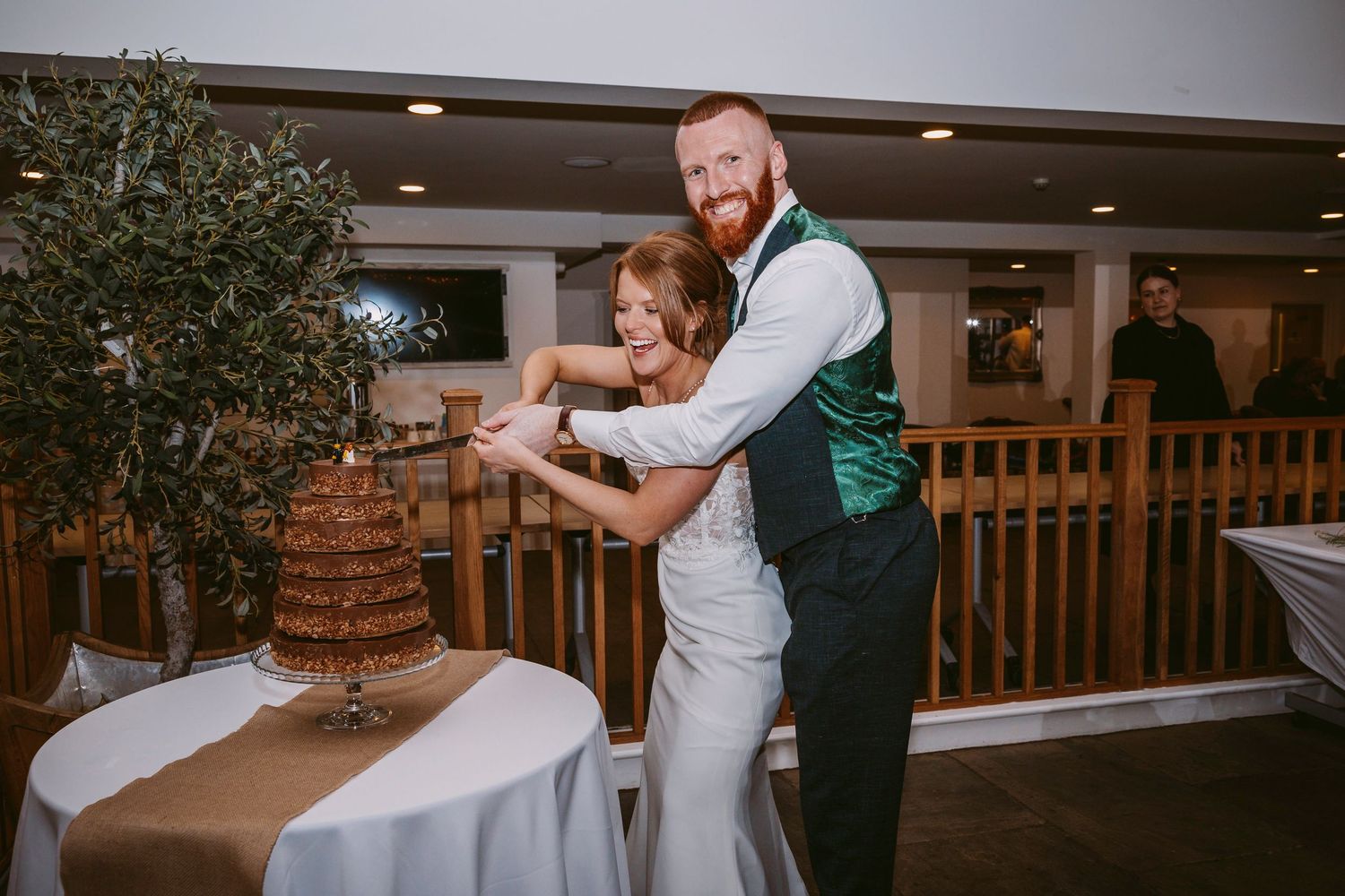 Newlyweds cutting their rustic naked wedding cake together at reception venue.