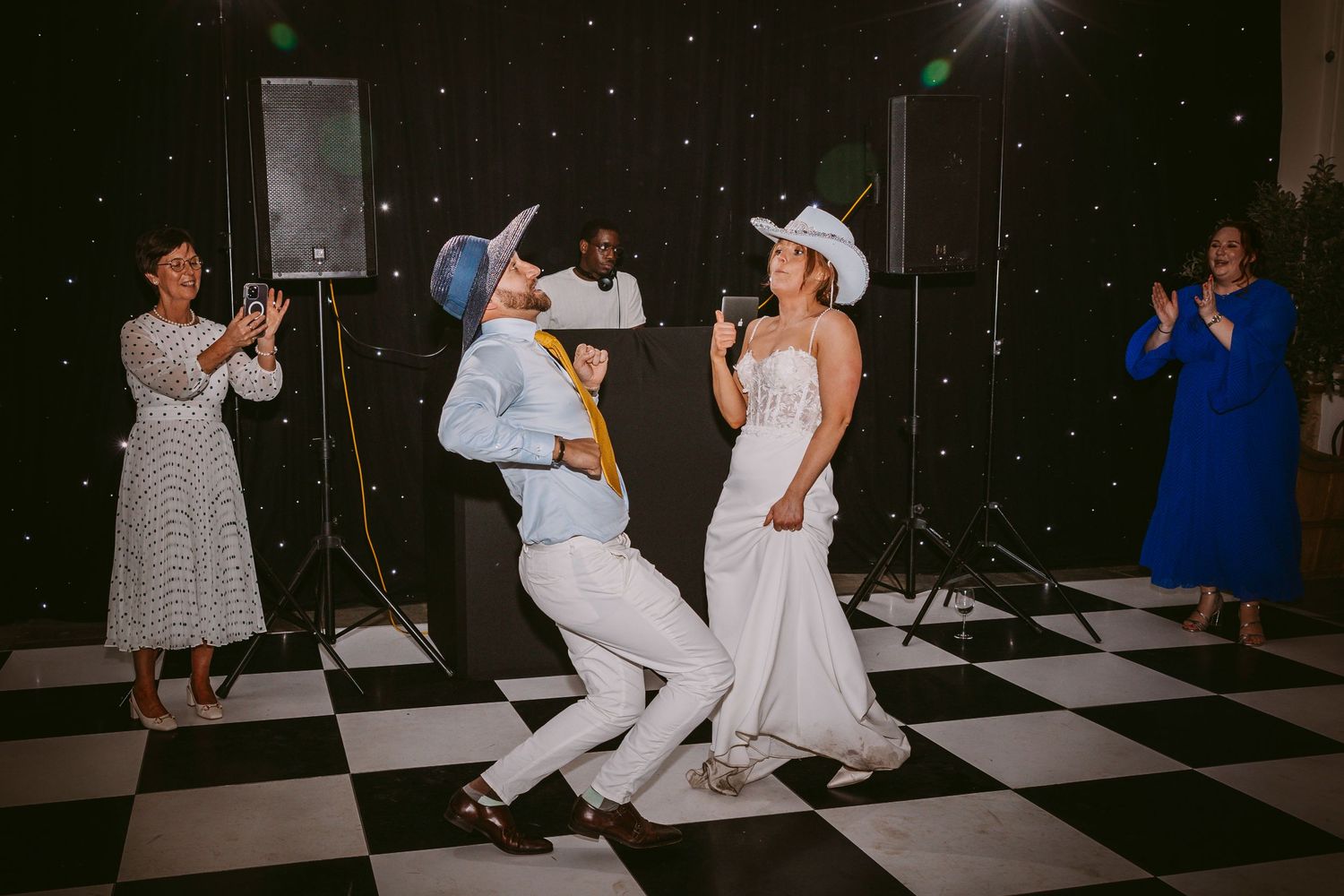 Couples dance in coordinated poses on a black and white checkered ballroom floor at night.