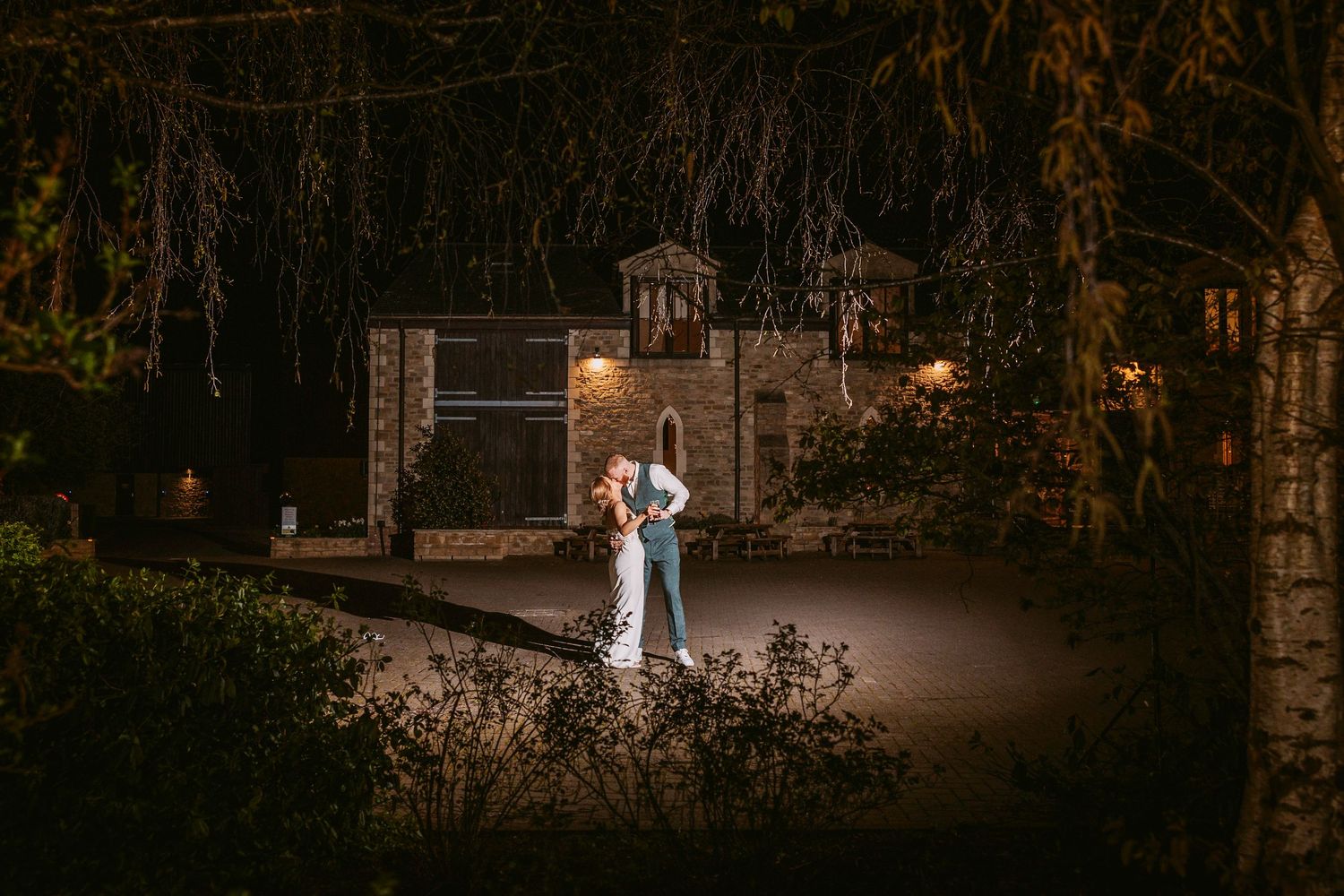 Golden light illuminates a romantic outdoor garden venue at dusk with ornate gates and stone architecture.