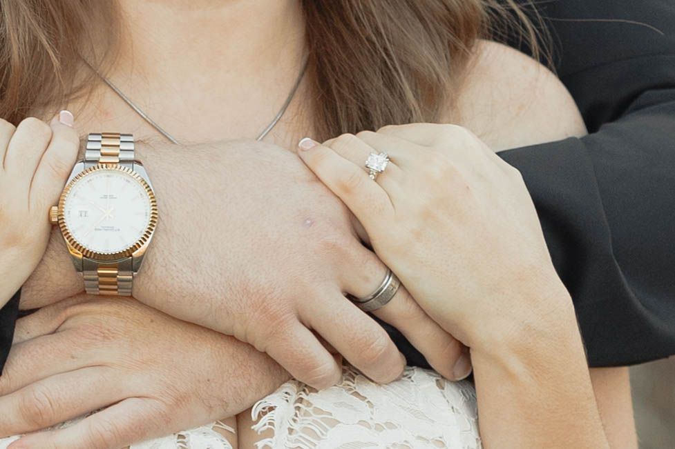 Close-up view of a silver wristwatch and an engagement ring showcasing delicate jewelry and accessories.