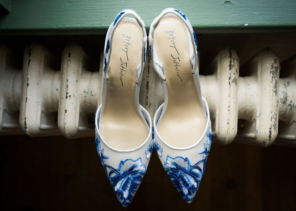 Elegant white and blue floral print pointed-toe heels placed atop a vintage radiator.