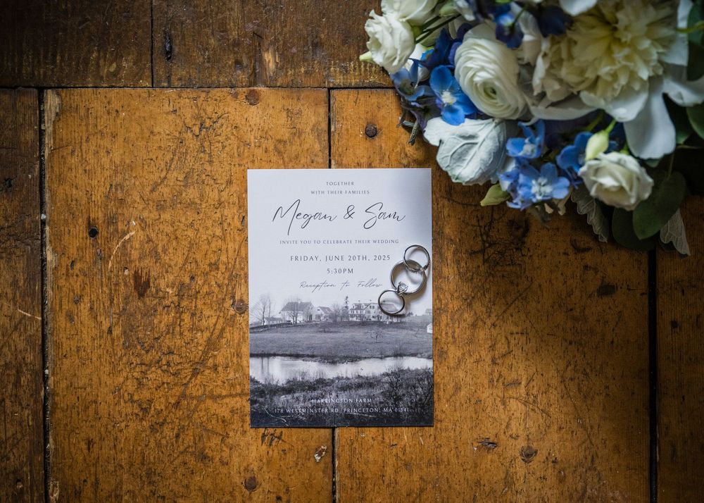 Wedding rings and invitation cards lie beautifully arranged on rustic wooden surface with hydrangea flowers.
