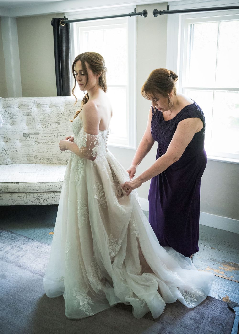 A wedding dress fitting scene in a bright room with an elegant white gown being adjusted before the ceremony.
