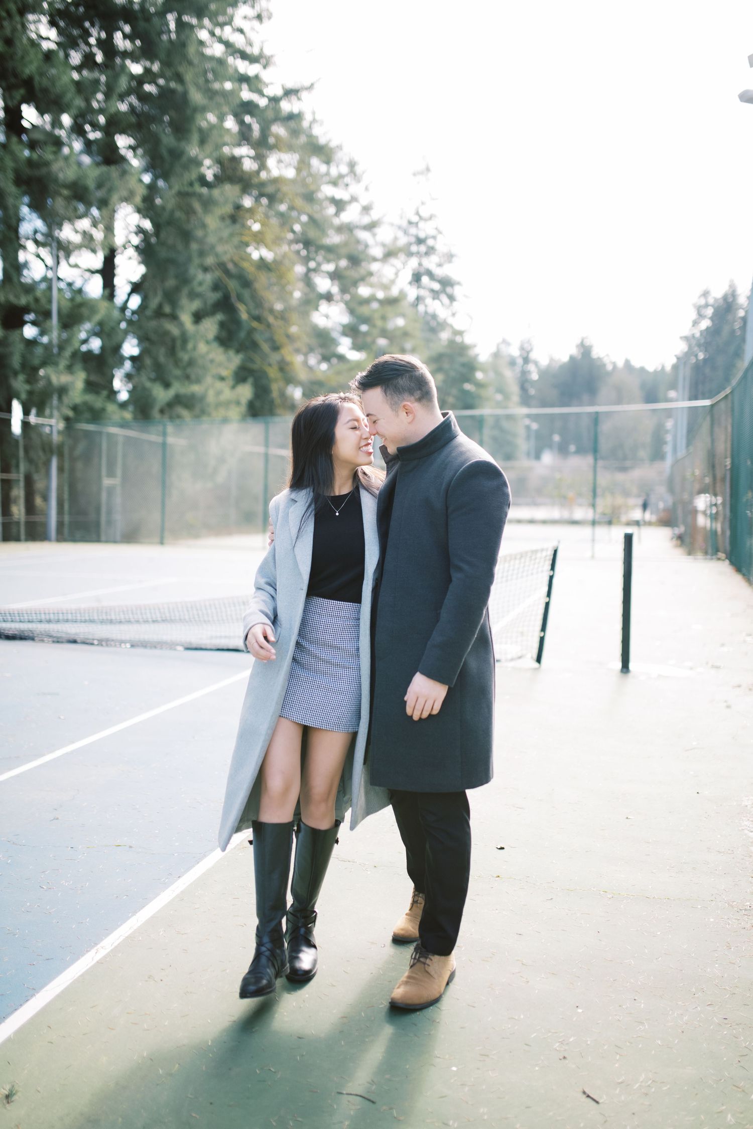 A romantic couple sharing intimate moments on a tennis court in casual winter outfits.