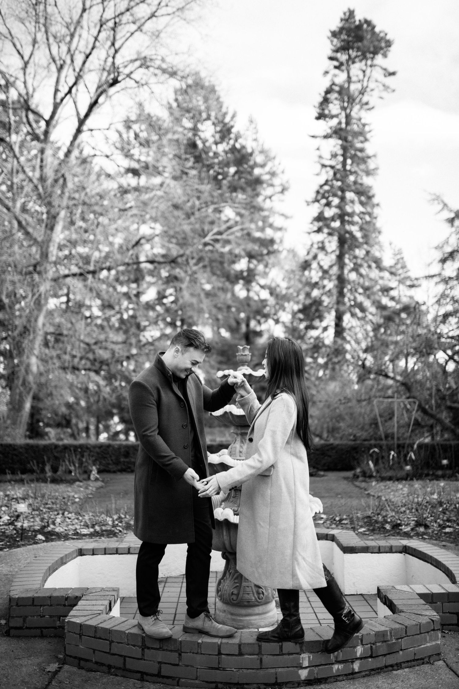 A couple sharing tender moments while sitting on brick steps surrounded by autumn trees.