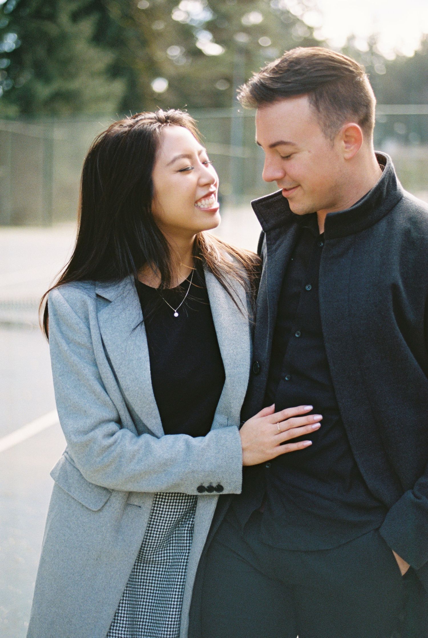 A candid photo of a laughing couple in winter coats sharing a joyful moment outdoors.