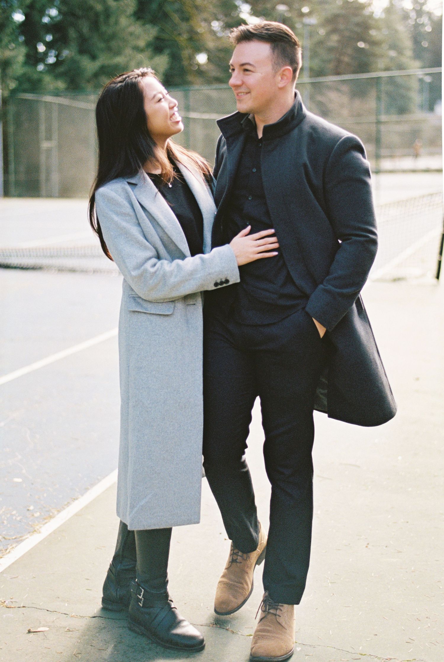 Couple in coordinating coats share a tender moment outdoors.