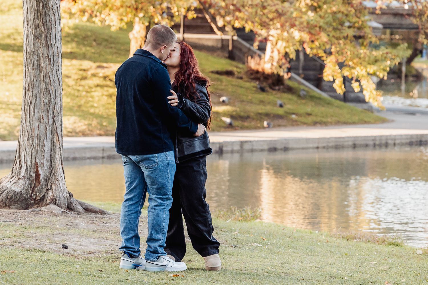 Happy couple sharing intimate moment by lake with fall colors.
