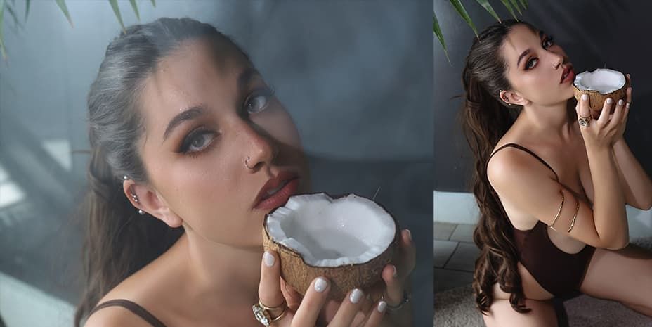 Woman in black dress poses dramatically with fresh coconut in moody tropical setting against misty jungle background.