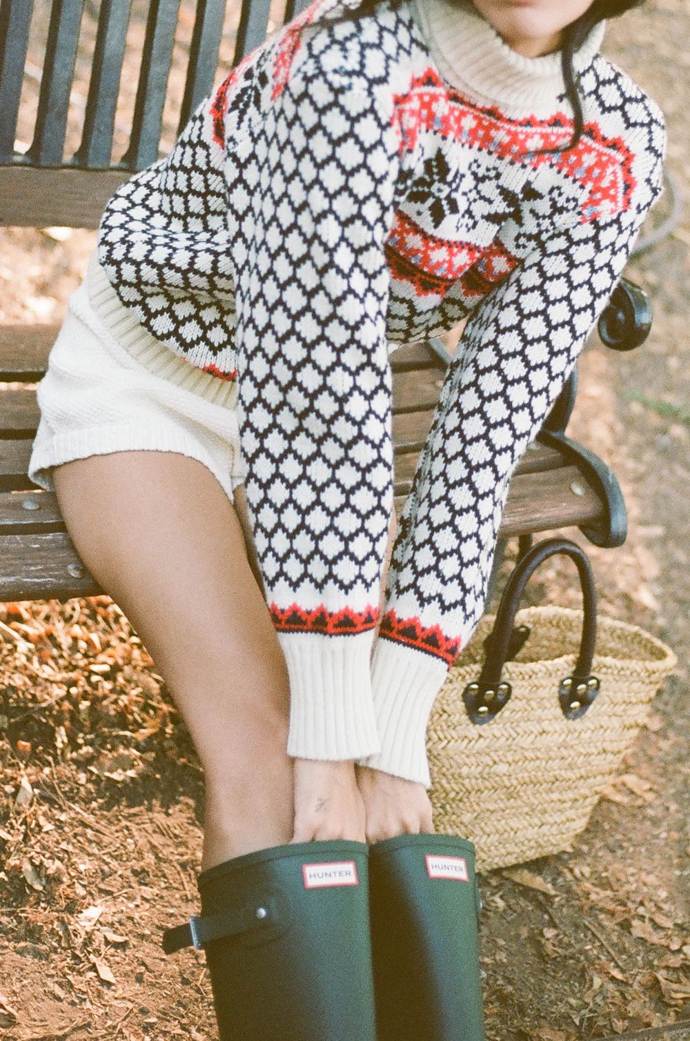 Close-up detail of Nordic pattern sweater with white shorts and green wellington boots.
