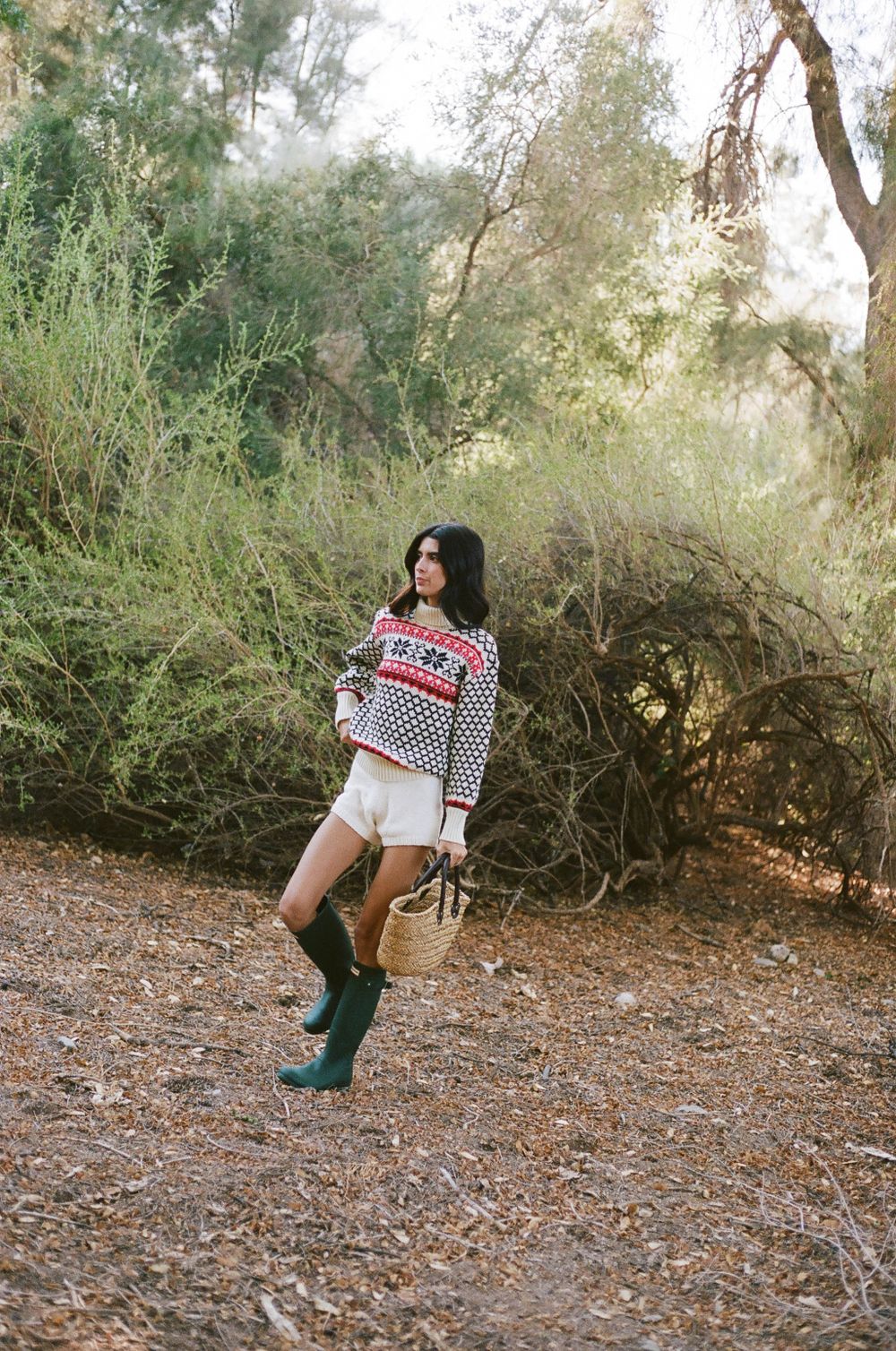 Fair isle sweater and white shorts styled with green rain boots in natural outdoor setting.