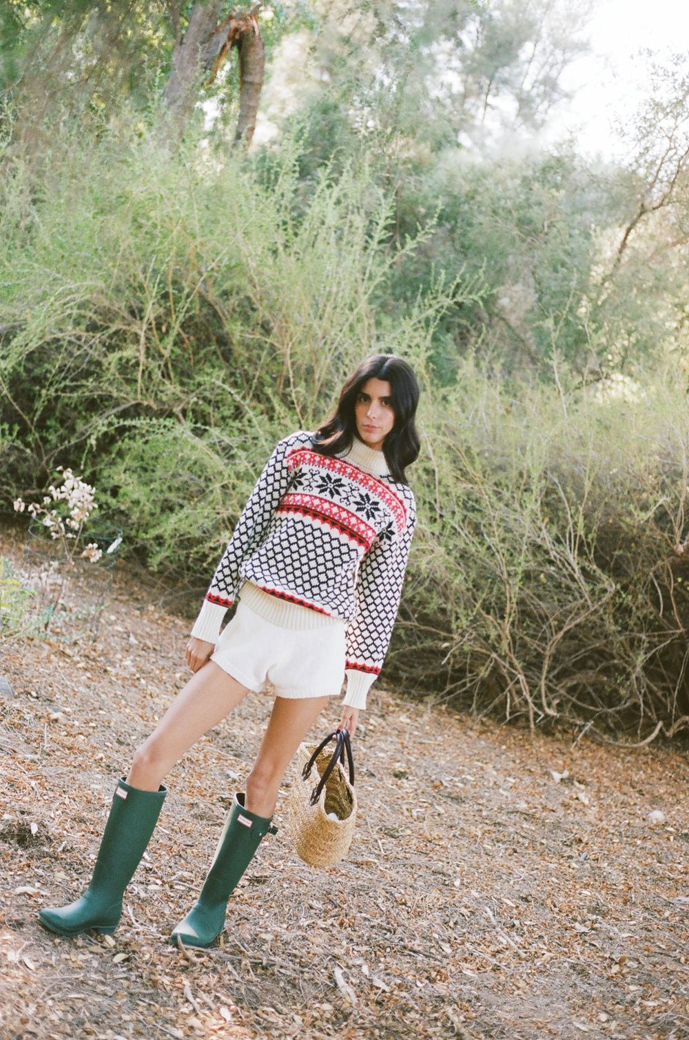 Winter outfit featuring patterned sweater, white shorts and green wellington boots against natural backdrop.