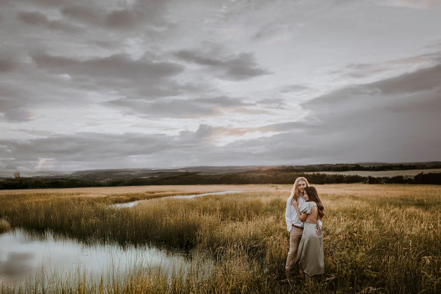 Image of couple standing in the middle of tall grass at dusk