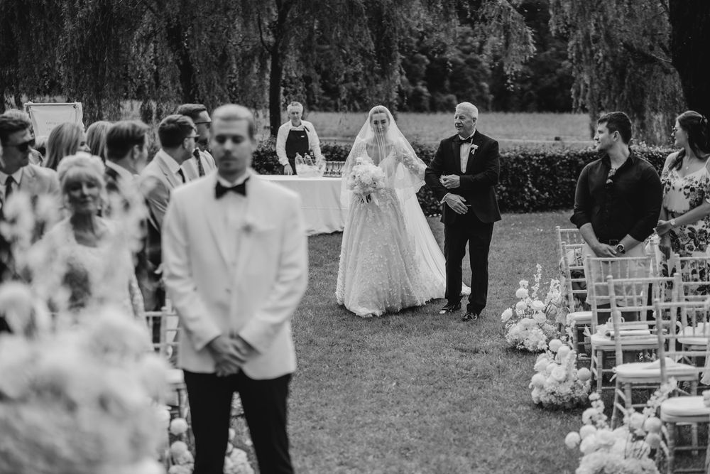 A couple celebrates their first dance at an outdoor garden wedding reception surrounded by seated guests.