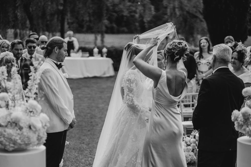 Outdoor wedding celebration with guests dancing on a lawn during sunset.