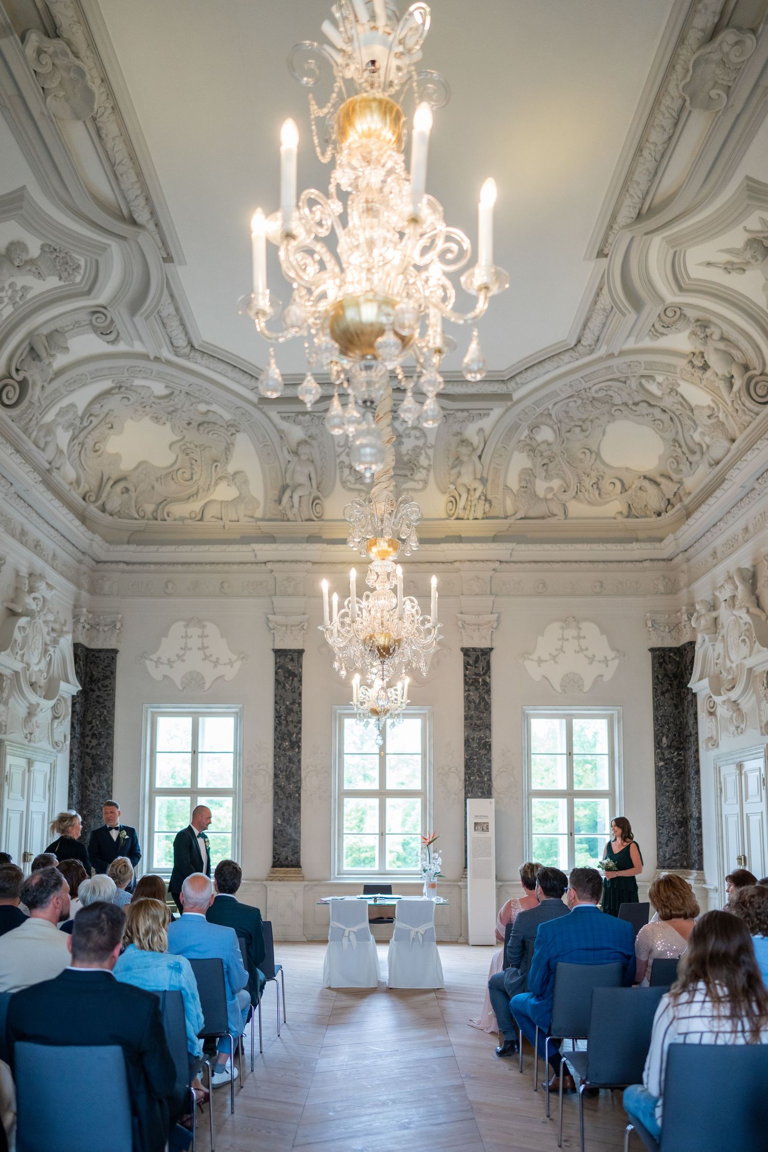 Hochzeitsreportage Schloss Mirow – Blick auf Kronleuchter und Brautpaar im Trausaal
