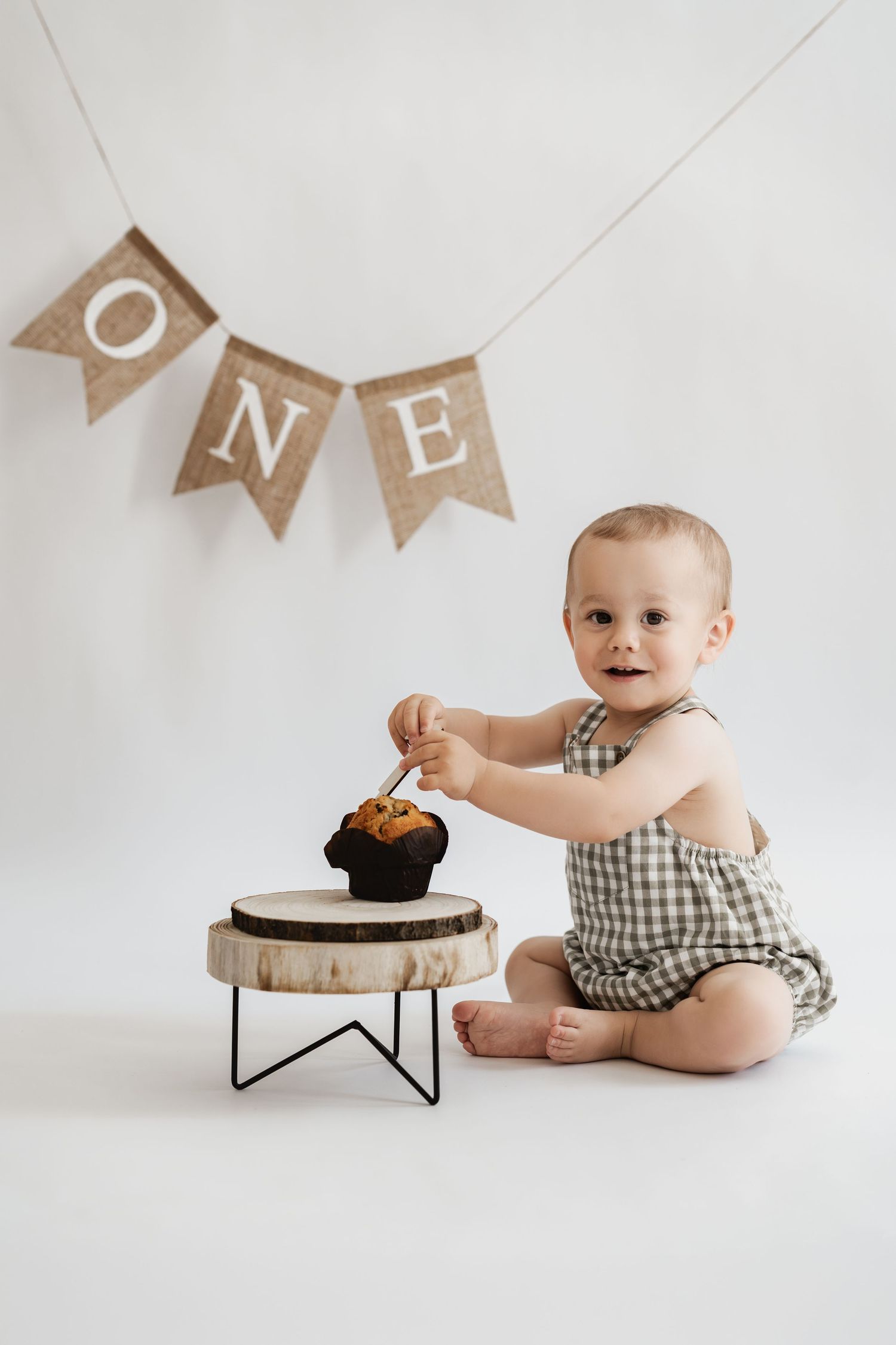 Kleiner Junge beim Geburtstagsfotoshooting im Fotostudio Stockerau, natürliches Geburtstagsfoto, Cake-Smash-Foto mit Muffin und Girlande