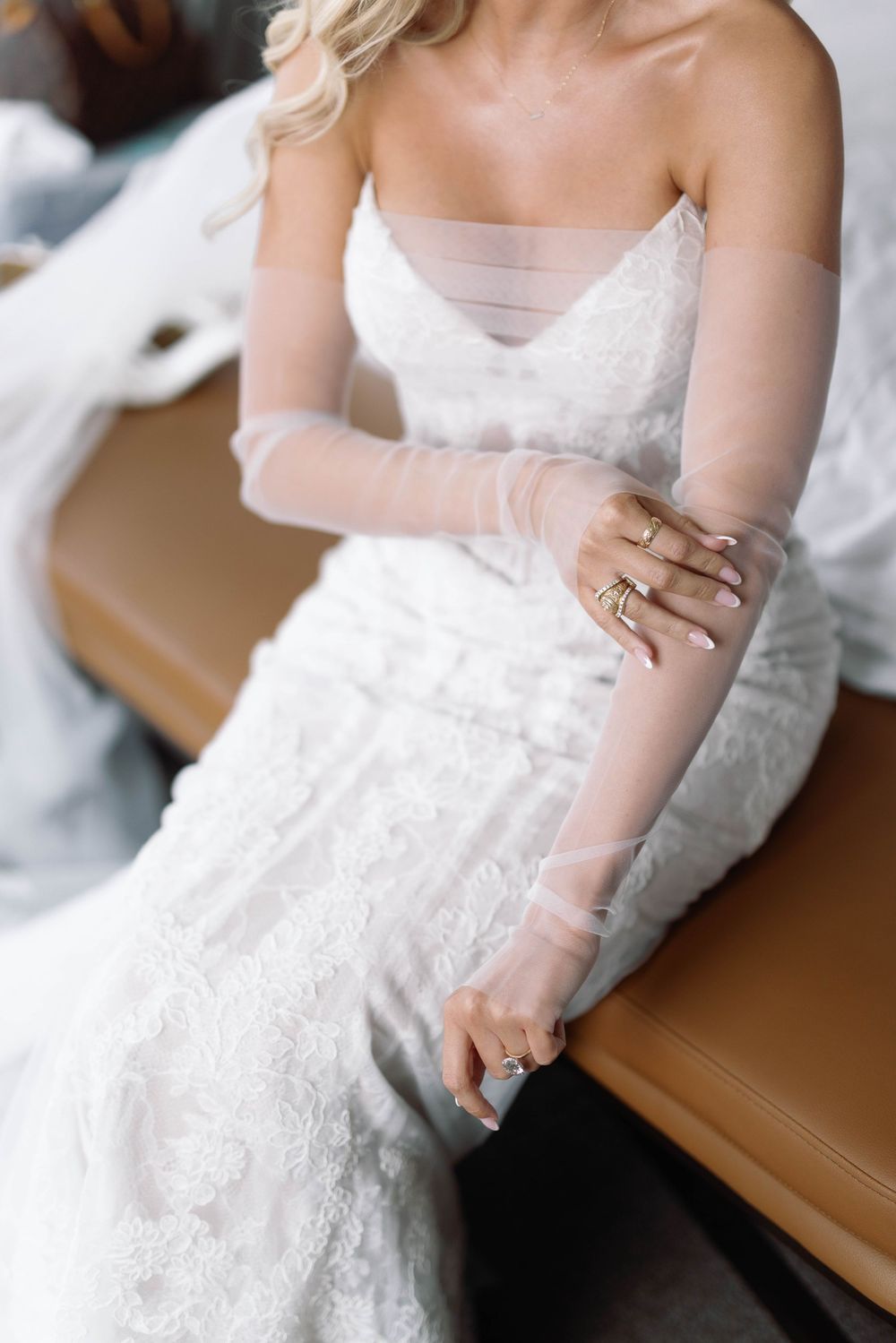 Close-up detail shots of delicate white lace wedding dress with sheer overlay and elegant ring accessories.