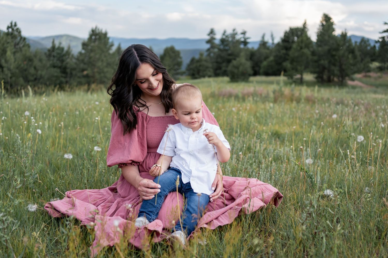 Mother and child sitting together in a field of wildflowers wearing coordinating pink and white outfits.