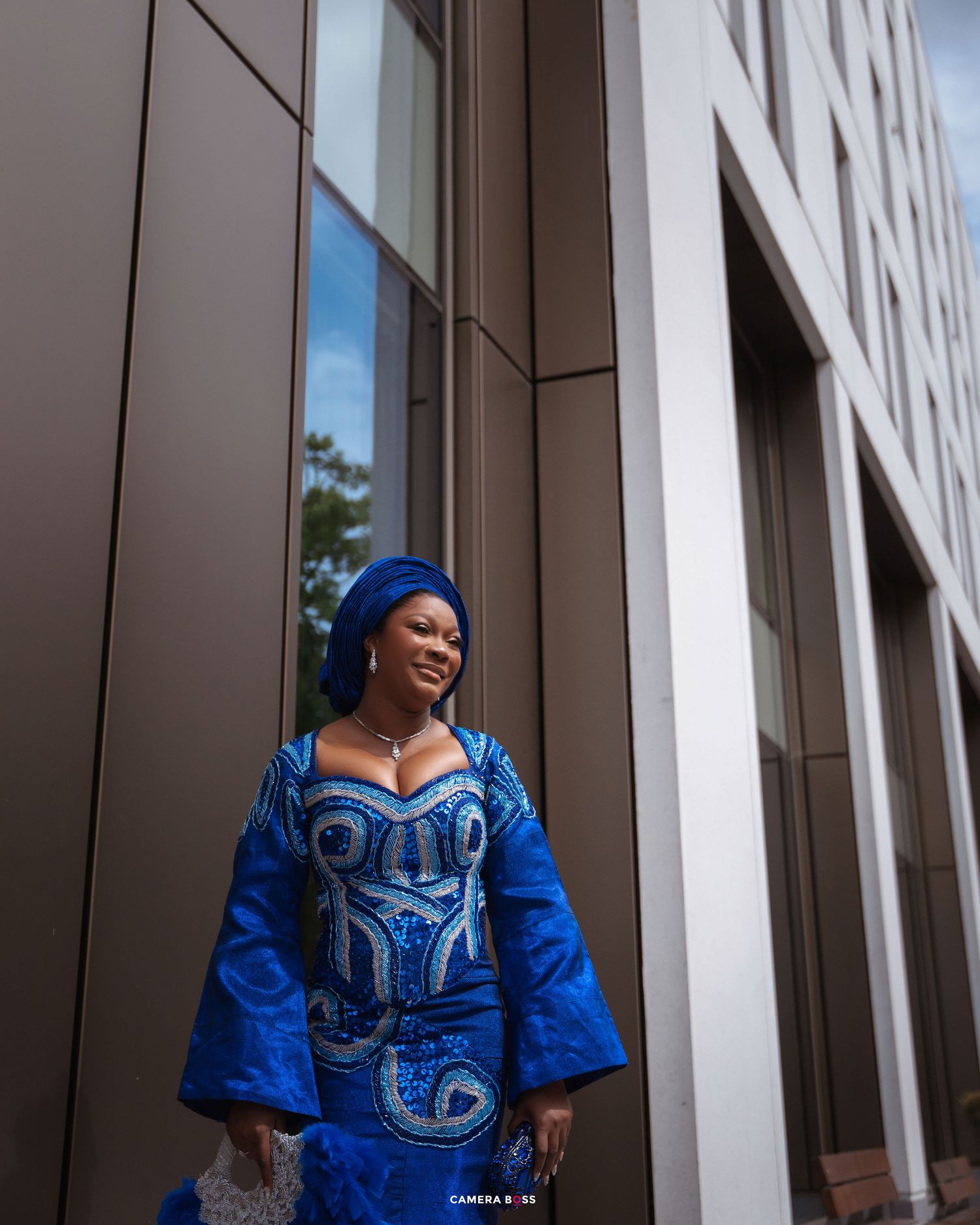 People wearing bright blue traditional African attire pose against a modern building facade.